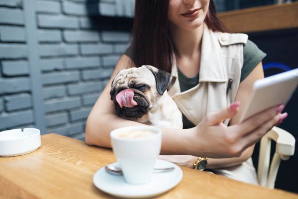 Una mujer con su perro tomando un café y trabajando